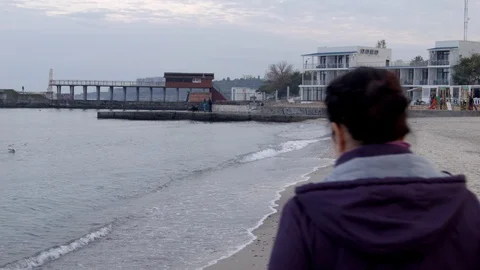 4K Shot from back. The woman appears from behind the camera and walks along the Stock-Footage 100126053