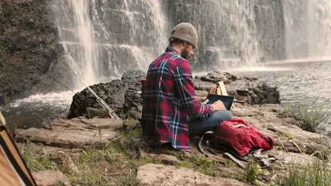 4k shot of camping man and trekker using banking app on touchscreen at waterfall Stock Footage 199621189