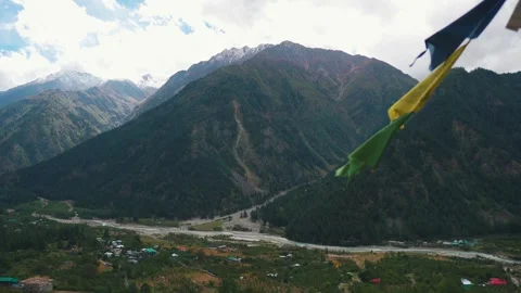 4K shot of clouds above mountains, village houses in valley and prayer flags flu Stock Footage 331805204