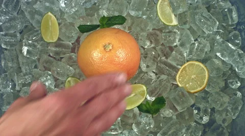 4k Shot of Cold Ice Cubes and Hand Places Orange Video stock 67459601