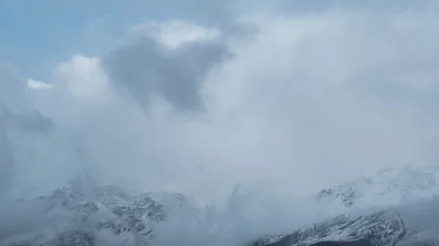 4k shot of dark storm clouds on snow covered mountains during winter season in L Stock Footage 258545384