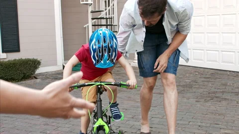 4k shot of father teaching son how to ride his bike and mother guiding her son o Video stock 201094222