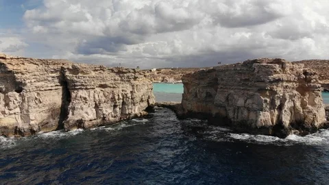 4K shot looking through a rock formation with Malta's blue lagoon visible beyond Video stock 102383454