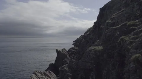4k shot of rocky cliffs over a moving sea on a sunny day with clouds Stock Footage 56703034