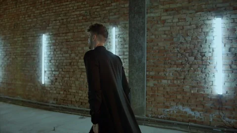 4K The shot from side of a walking man in black who truns back and continues to Vidéo 102852471