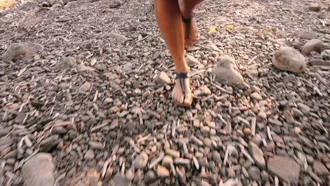 4k shot of woman's legs working at sunset on stone beach with sandals. Stock Footage 199617192