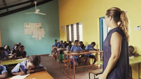 4k of side view of teacher explaining english alphabet off chalkboard in classro Stock Footage 199625160