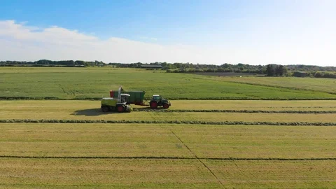 [4K] Side-View of two Tractors collecting grass from field | Aerial Shot Stock Footage 94295564