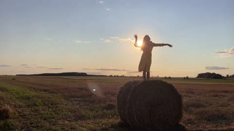 4k Silhouette of dancing woman on a stack of hay on a field against a sun light. Stock Footage 160539762