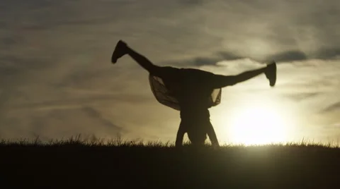 4K Silhouette of young child doing cartwheels at sunset, in slow motion Stock Footage 62189598
