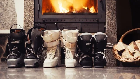 4k Ski Boots lined up before fireplace near basket of kindling Stock-Footage 118943839
