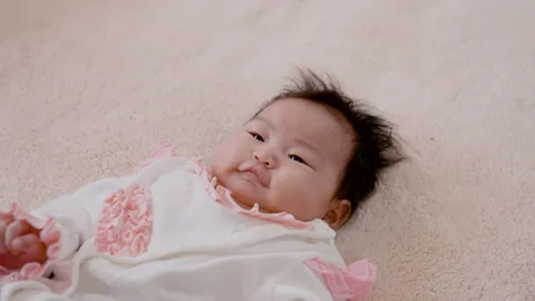 4K Slow Motion, Close Up A 3-month-old newborn girl lies in her bed waving Stock Footage 203893852