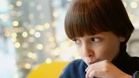 4K slow motion close up of boy drinking beverage through straw in cozy cafe. Stock Footage 329301092
