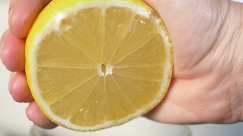 4k, slow-motion, close-up. hand compressing lemon. squeeze out lemon juice Stock Footage 84160416