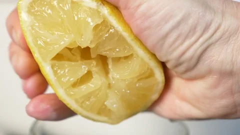 4k, slow-motion, close-up. hand compressing lemon. squeeze out lemon juice Stock Footage 84160565
