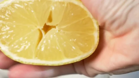 4k, slow-motion, close-up. hand compressing lemon. squeeze out lemon juice Stock Footage 84199063