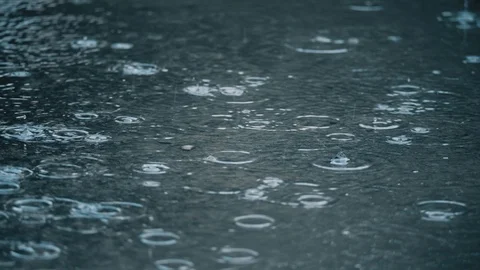 4K slow motion establishing shot of rain falling on pavement. Stock Footage