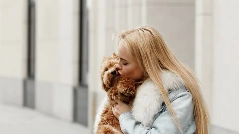 4k slow motion of happy young woman kissing her cute maltipoo dog outdoors. 스톡 동영상 334862631