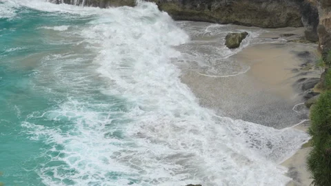 4K slow motion high angle view of ocean waves crashing on Kelingking Beach sand 스톡 동영상 337088453