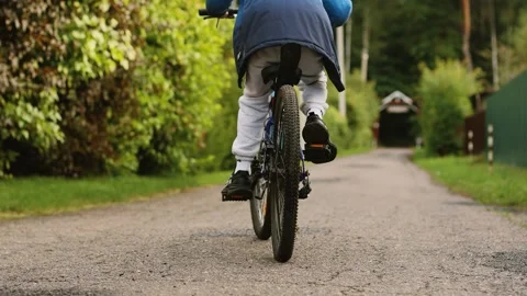 4K slow motion of a little boy riding a bicycle on a country road from behind Stock Footage 344880733