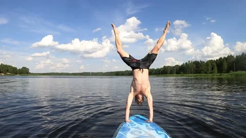 4K slow-motion man doing a handstand on a paddleboard SUP and falling in water Stock Footage 157106553
