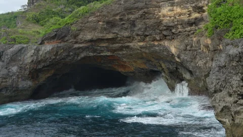 4K slow motion medium shot of waves rushing into a volcanic sea cave 스톡 동영상 337088491