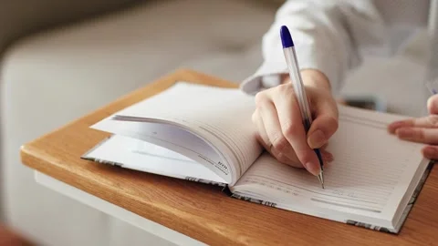 4K slow motion of a person hand writing with a pen in an open notebook. Видео 346069194
