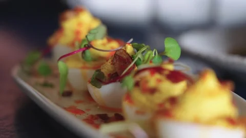 4K slow motion push-in footage of deviled eggs drizzled with sauce and topped Stock Footage 332137206
