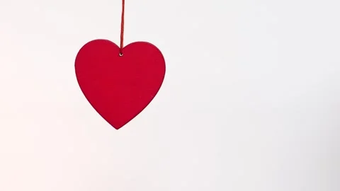 4K slow motion red heart hanging on white background. Minimal romantic symbol Stock Footage 327239373