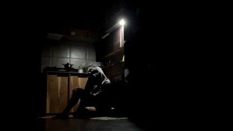 4K Slow Motion Silhouette of a Man in Hoodie Standing Up from a Dark Kitchen Cha Stock Footage 338170938