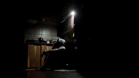 4K Slow Motion Silhouette of a Man in Hoodie Sitting in a Dark Kitchen at Night Stock Footage 338170956