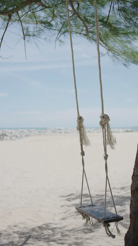 4K Slow motion a swing moving slowly with a beach background Stock Footage 337174083