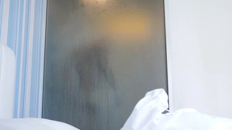 4k, slow motion. unrecognizable guy takes a shower. someone looks at it through Vidéo 86667864