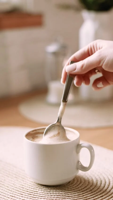 4K slow motion vertical close up of woman stirring cappuccino in cozy kitchen Stock Footage 329301097