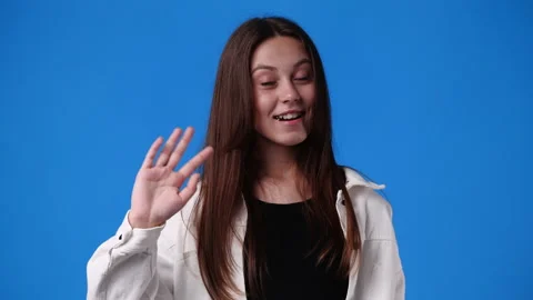 4k slow motion video of cute girl waving hello on blue background. Stock Footage 226699393