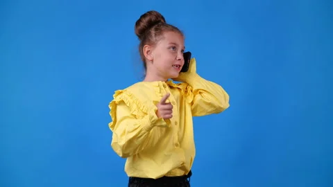 4k slow motion video of cute girl talking over the phone on blue background. Stock Footage 227530531