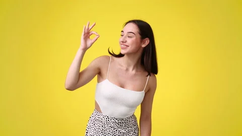 4k slow motion video of cute girl showing OK sign on yellow background. Stock Footage 228721524