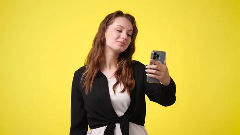 4k slow motion video of cute girl using phone over yellow background. Stock Footage 228780752