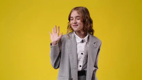 4k slow motion video of cute girl waving hello on yellow background. Stock Footage 229712410