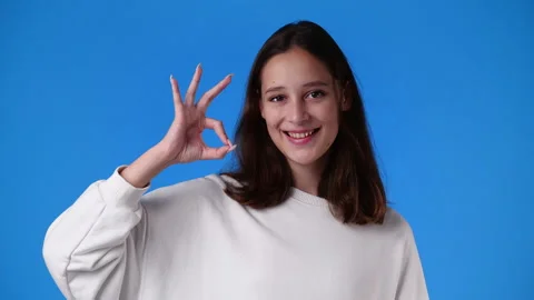 4k slow motion video of cute girl showing OK sign on blue background. Stock Footage 231337493