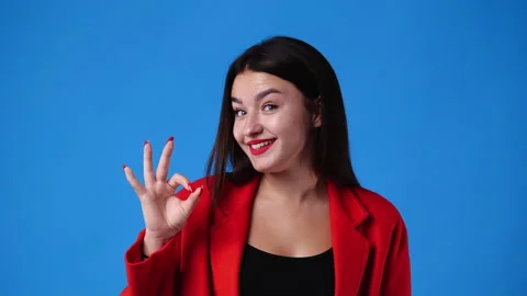 4k slow motion video of cute girl showing OK sign on blue background. Stock Footage 231404114