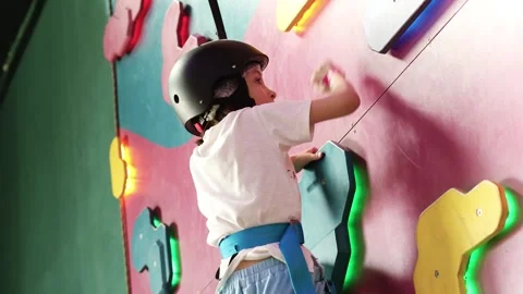 4K Slow motion video of a cute little boy in a black safety helmet climbing a 库存影片 341682495