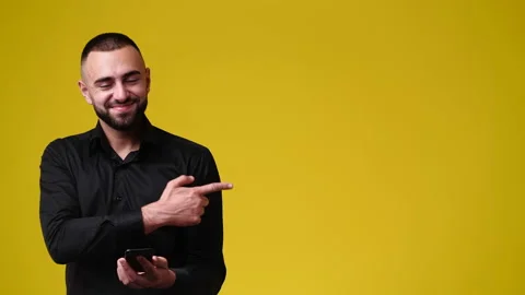 4k slow motion video of man using phone and pointing at right side over yellow Stock Footage 227505491