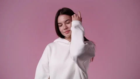 4k slow motion video of one girl in white hoodie posing for a video on pink Stock Footage 227410179