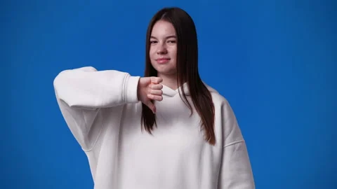 4k slow motion video of one girl showing thumb down on blue background. Stock Footage 227509859