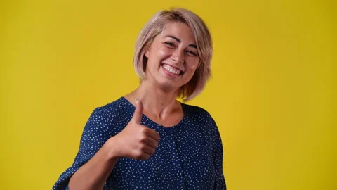 4k slow motion video of one woman thowing thumb up over yellow background. Stock Footage 227531660