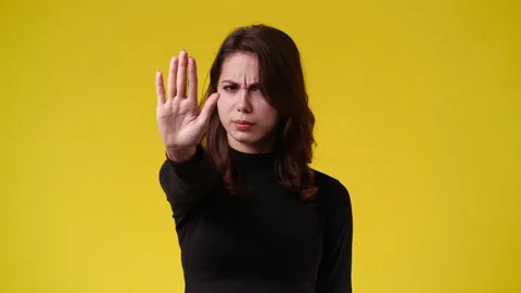 4k slow motion video of one girl showing stop sign over yellow background. Stock Footage 227744104