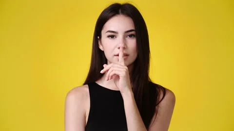 4k slow motion video of one girl showing silence sign on yellow background. Stock Footage 227749740