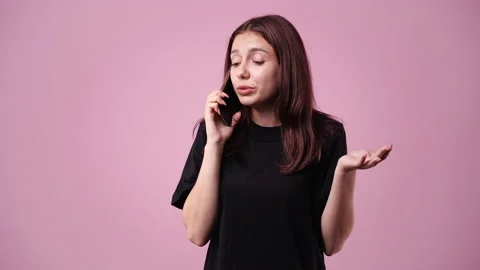 4k slow motion video of one girl talking over the phone on pink background. Stock Footage 228718226