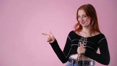 4k slow motion video of one girl pointing at left and showing thumb up over pink Stock Footage 228764367